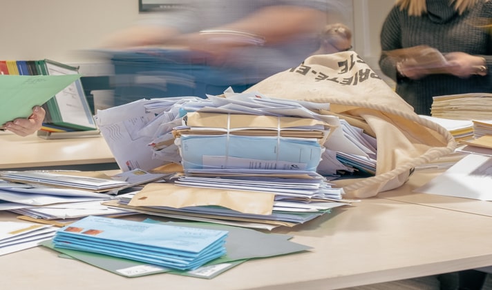 Een overvolle postzak die neerligt op tafel bij Merak